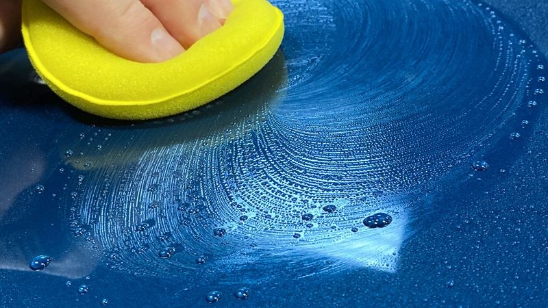 Close up of applying paint coating onto wet surface of vehicle.