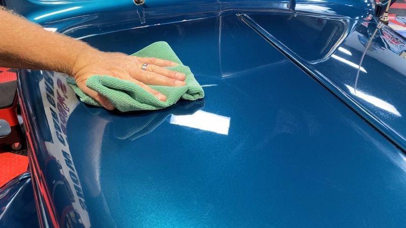 Buffing away paint coating from hood.