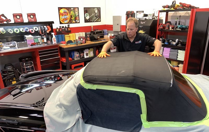 Rubbing RaggTopp Fabric Protectant into convertible top.