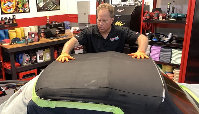 Rubbing RaggTopp Fabric Protectant into convertible top.
